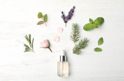 Photo of Essential oil and ingredients on wooden background, flat lay