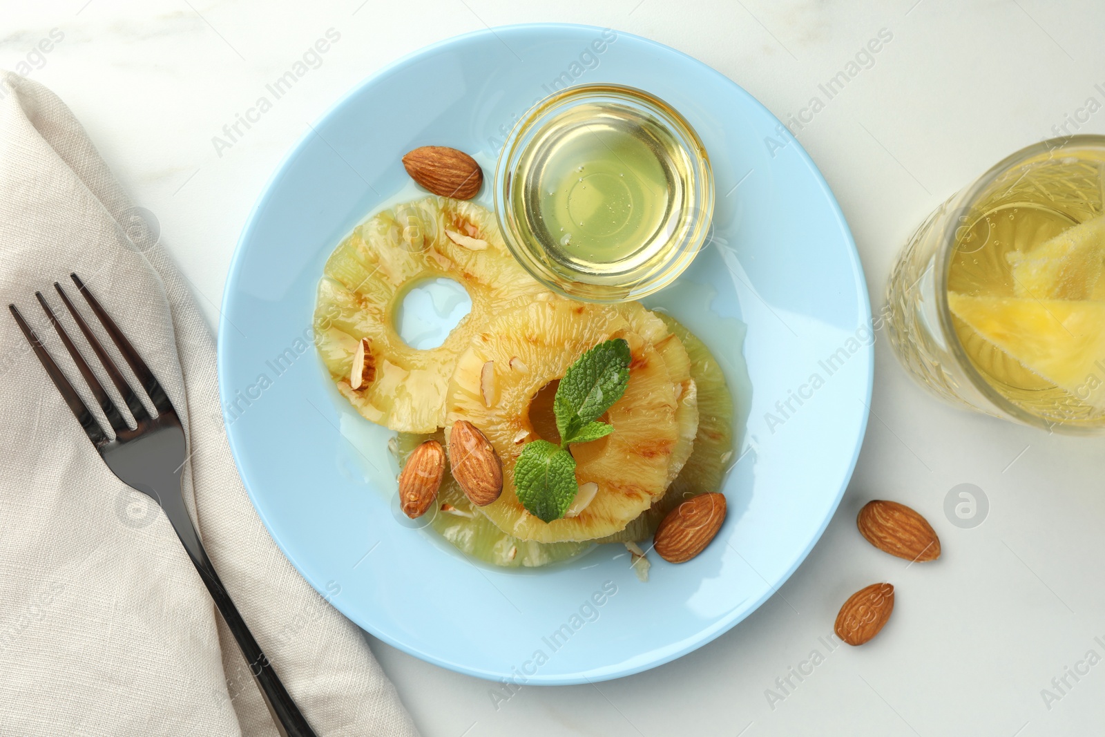 Photo of Tasty grilled pineapple slices served with mint, almonds and honey on white table, flat lay