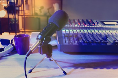 Photo of Microphone and professional mixing console on table in radio studio