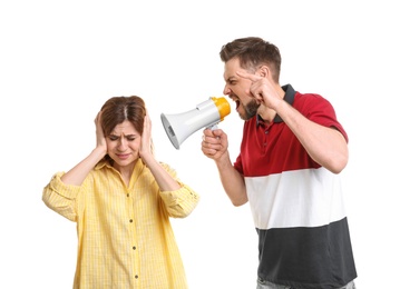 Young man with megaphone shouting at woman on white background