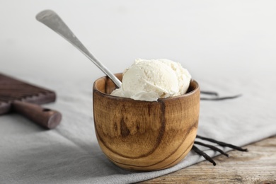 Photo of Wooden bowl with tasty vanilla ice cream on table