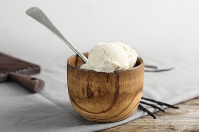 Wooden bowl with tasty vanilla ice cream on table