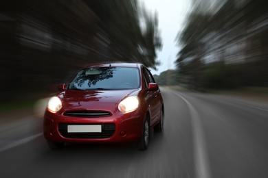 Image of Red car driving at high speed on asphalt road outdoors, motion blur effect