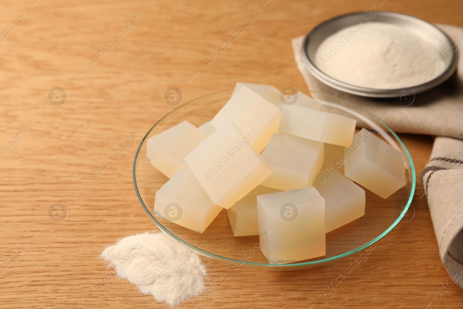 Photo of Agar-agar jelly cubes and powder on wooden table. Space for text