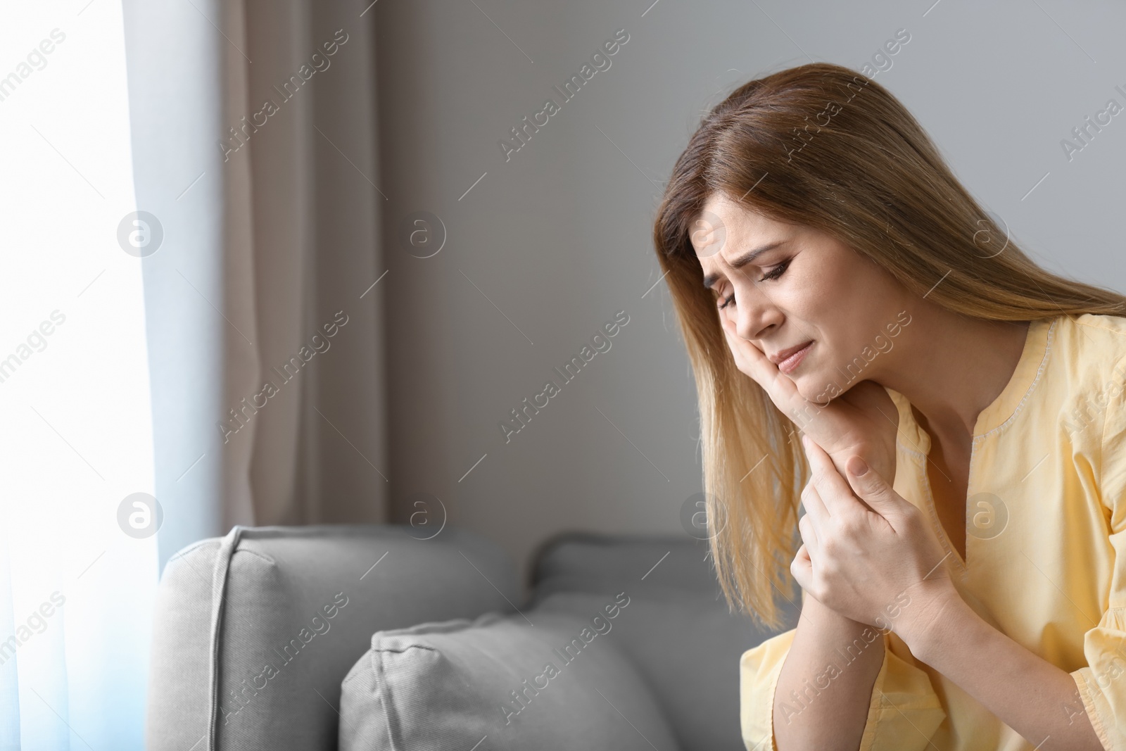 Photo of Young woman suffering from toothache at home