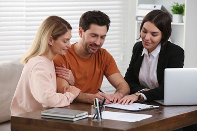 Photo of Professional notary helping couple with paperwork in office