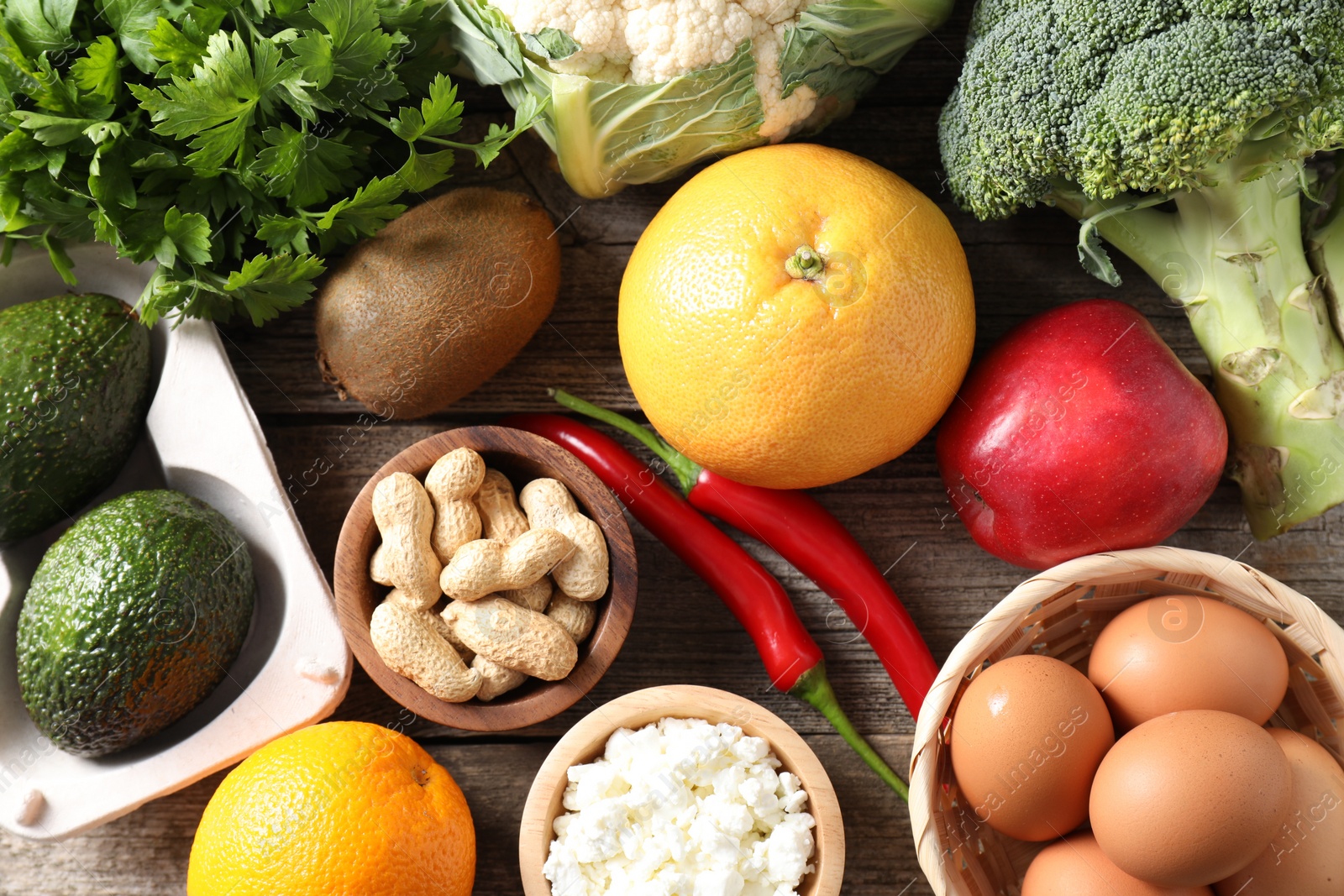 Photo of Healthy meal. Different vegetables and raw eggs on wooden table, flat lay