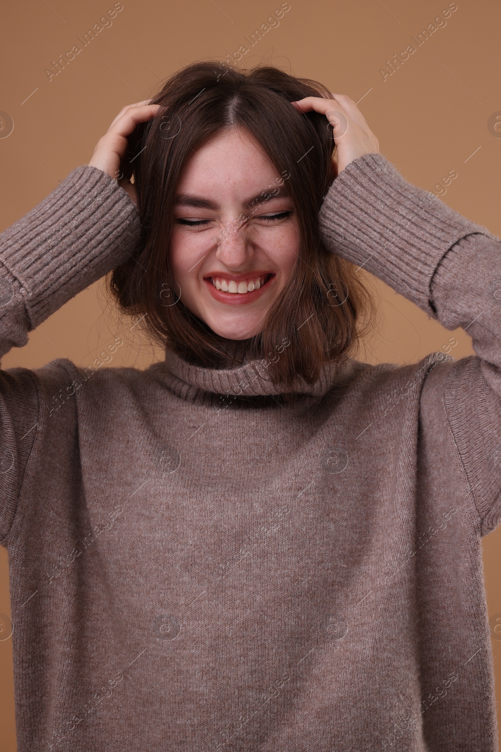 Photo of Portrait of beautiful young woman in warm sweater on brown background