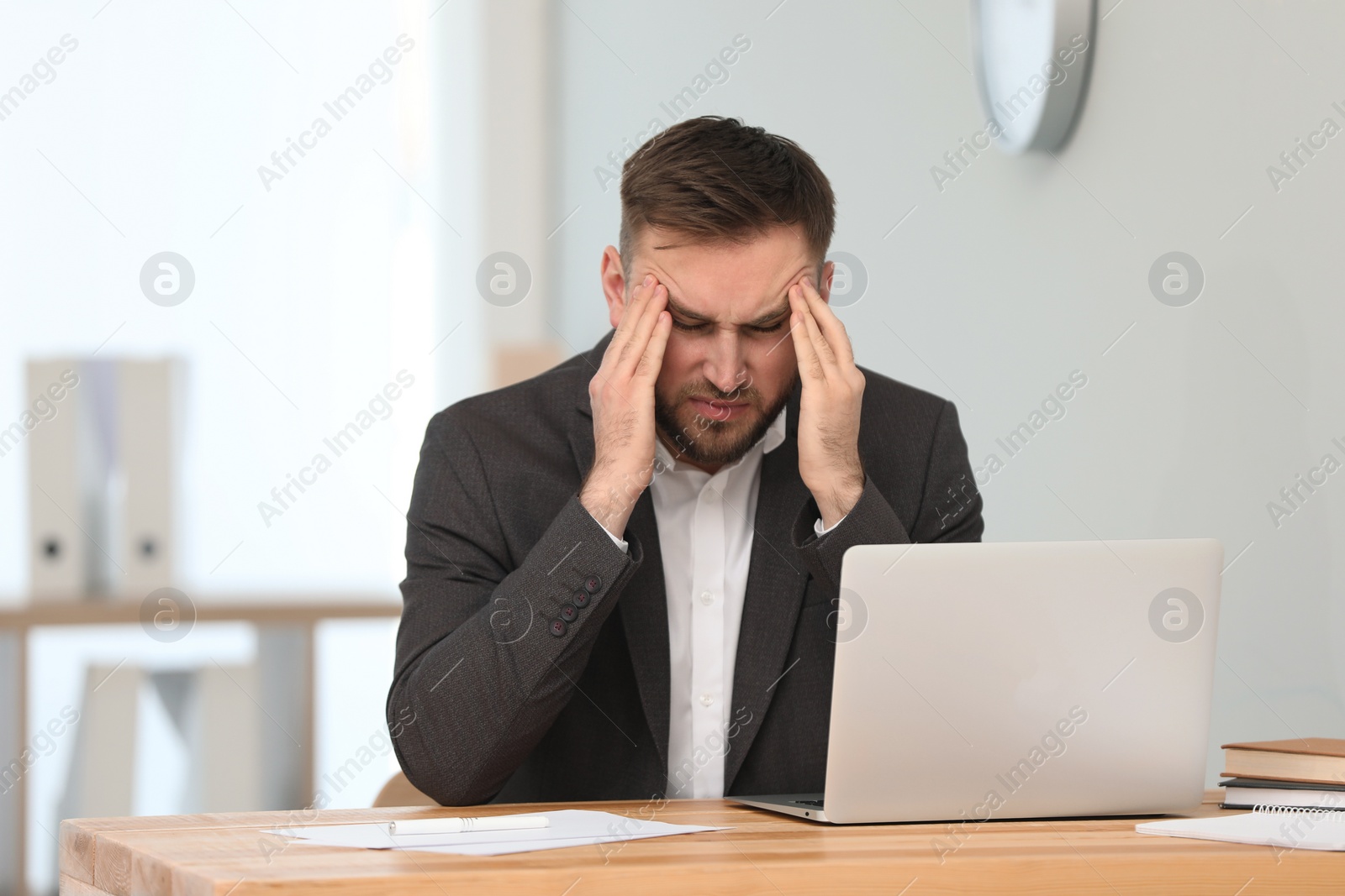 Photo of Man suffering from migraine at workplace in office