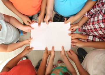 Little children holding sheet of paper in hands together, top view. Unity concept