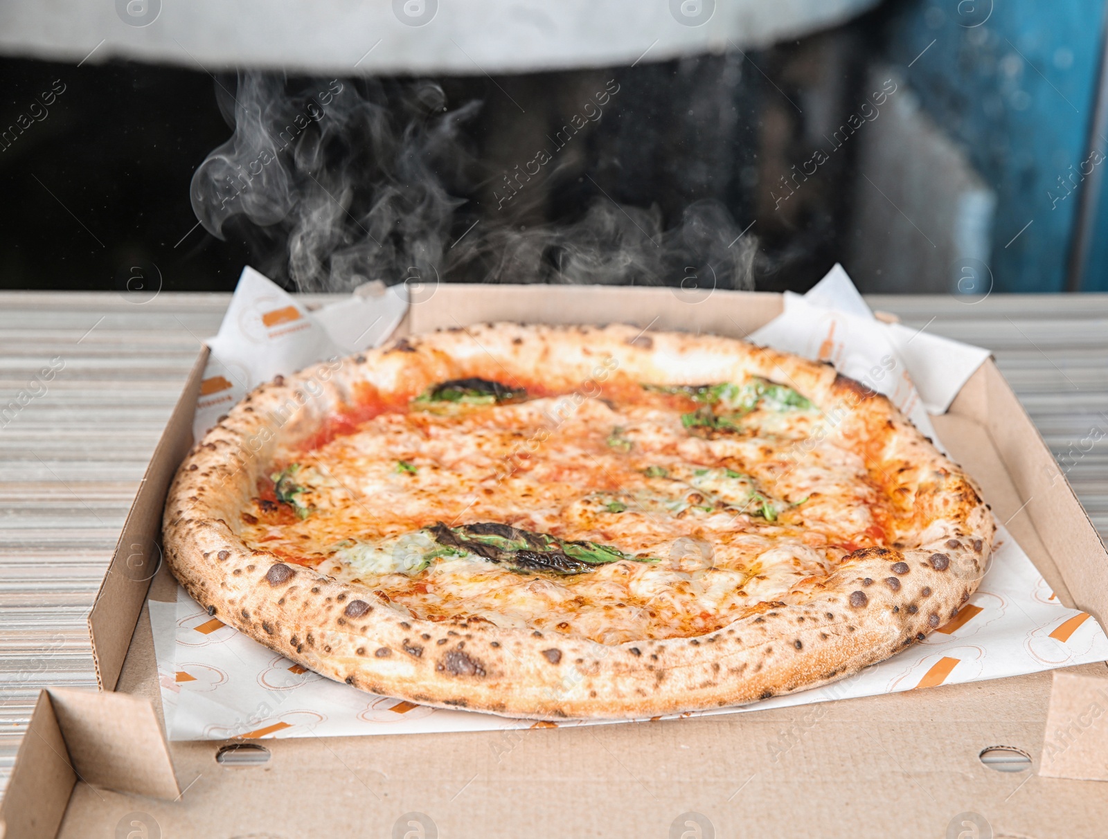 Photo of Tasty Italian oven baked pizza in delivery box on table