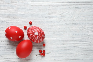 Photo of Flat lay composition with painted Easter eggs on wooden table, space for text