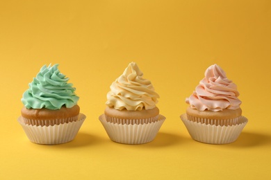 Photo of Tasty cupcakes with cream on yellow background