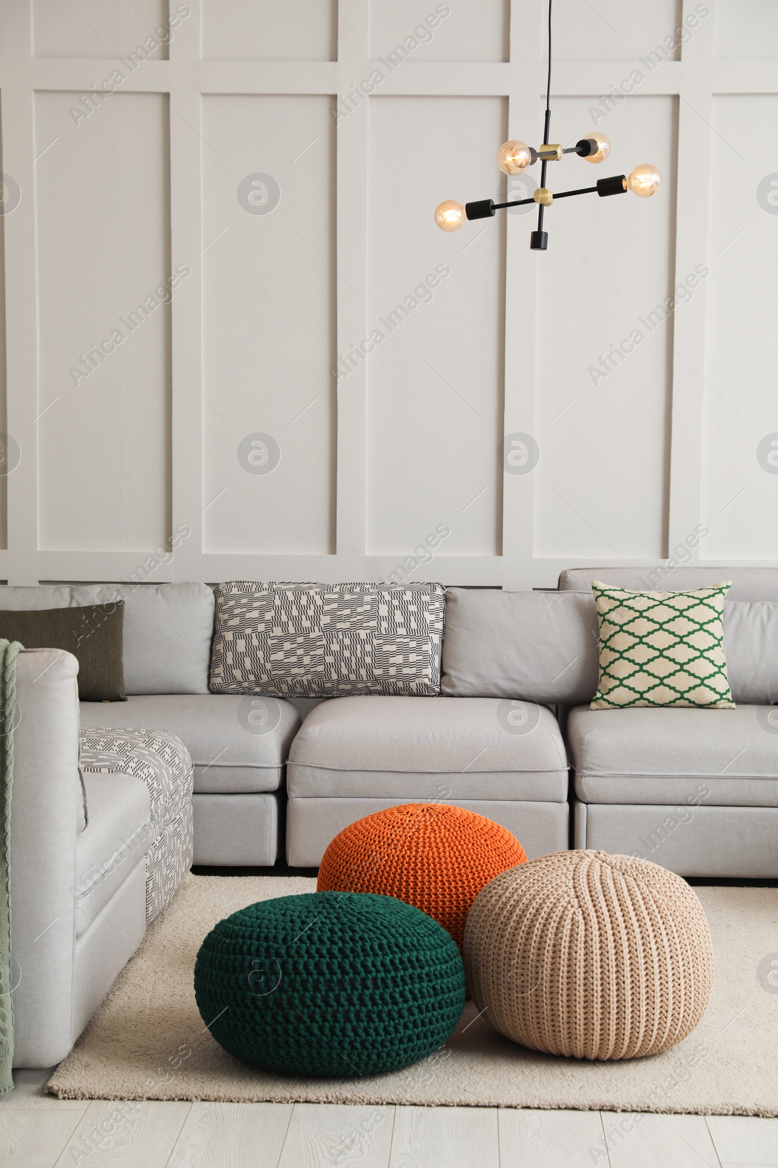 Photo of Living room interior with different stylish knitted poufs and sofa