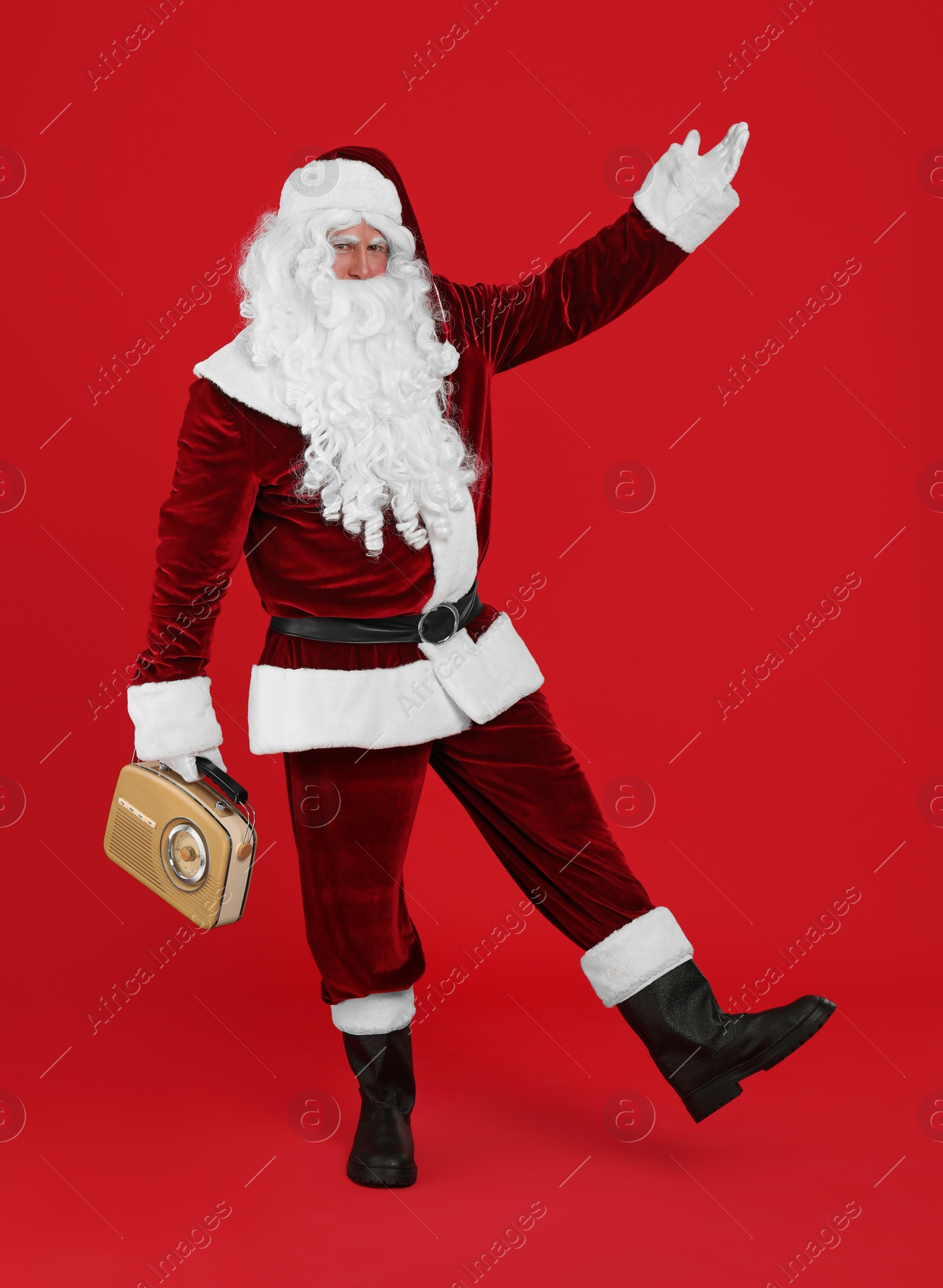 Photo of Santa Claus with vintage radio on red background. Christmas music