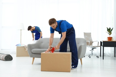 Photo of Young men in uniform working indoors. Moving service