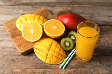 Photo of Tasty tropical drink with mango and fresh fruits on wooden table