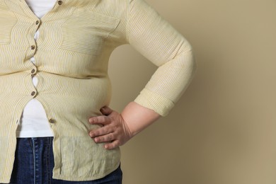 Photo of Overweight woman in tight shirt on beige background, closeup. Space for text