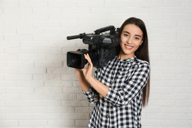 Photo of Operator with professional video camera near white brick wall
