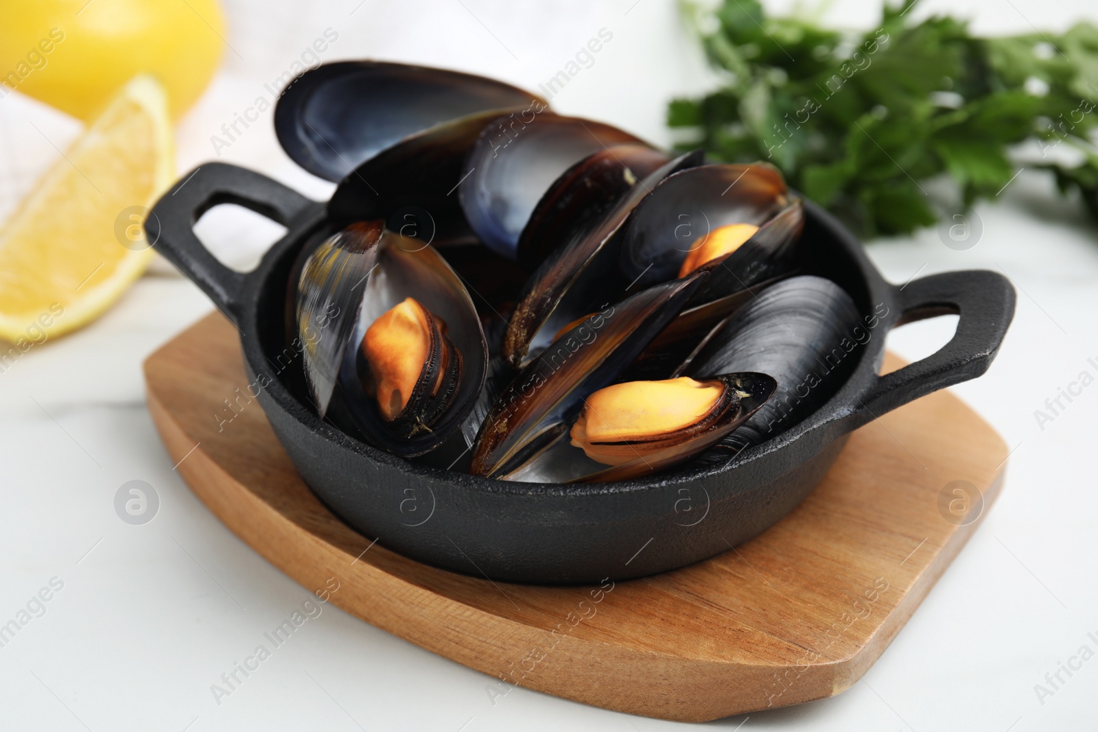 Photo of Pan of cooked mussels on white table, closeup