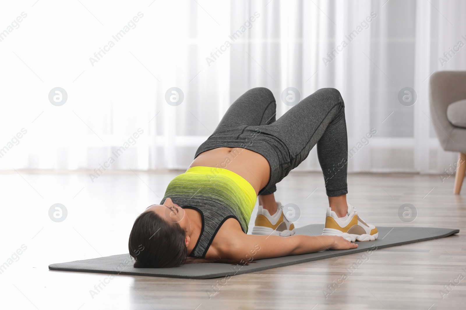 Photo of Young woman in fitness clothes doing exercise at home. Space for text