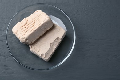 Photo of Compressed yeast on grey wooden table, top view. Space for text