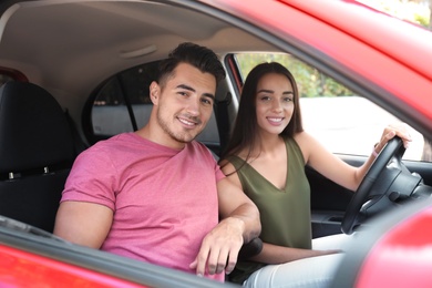 Happy young couple in car on road trip