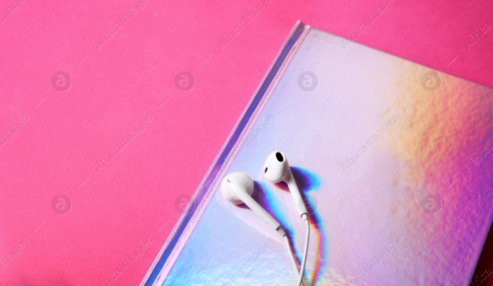 Photo of Stylish girl notebook and earphones on color background, closeup