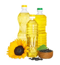 Photo of Bottles with sunflower cooking oil, seeds and yellow flower on white background