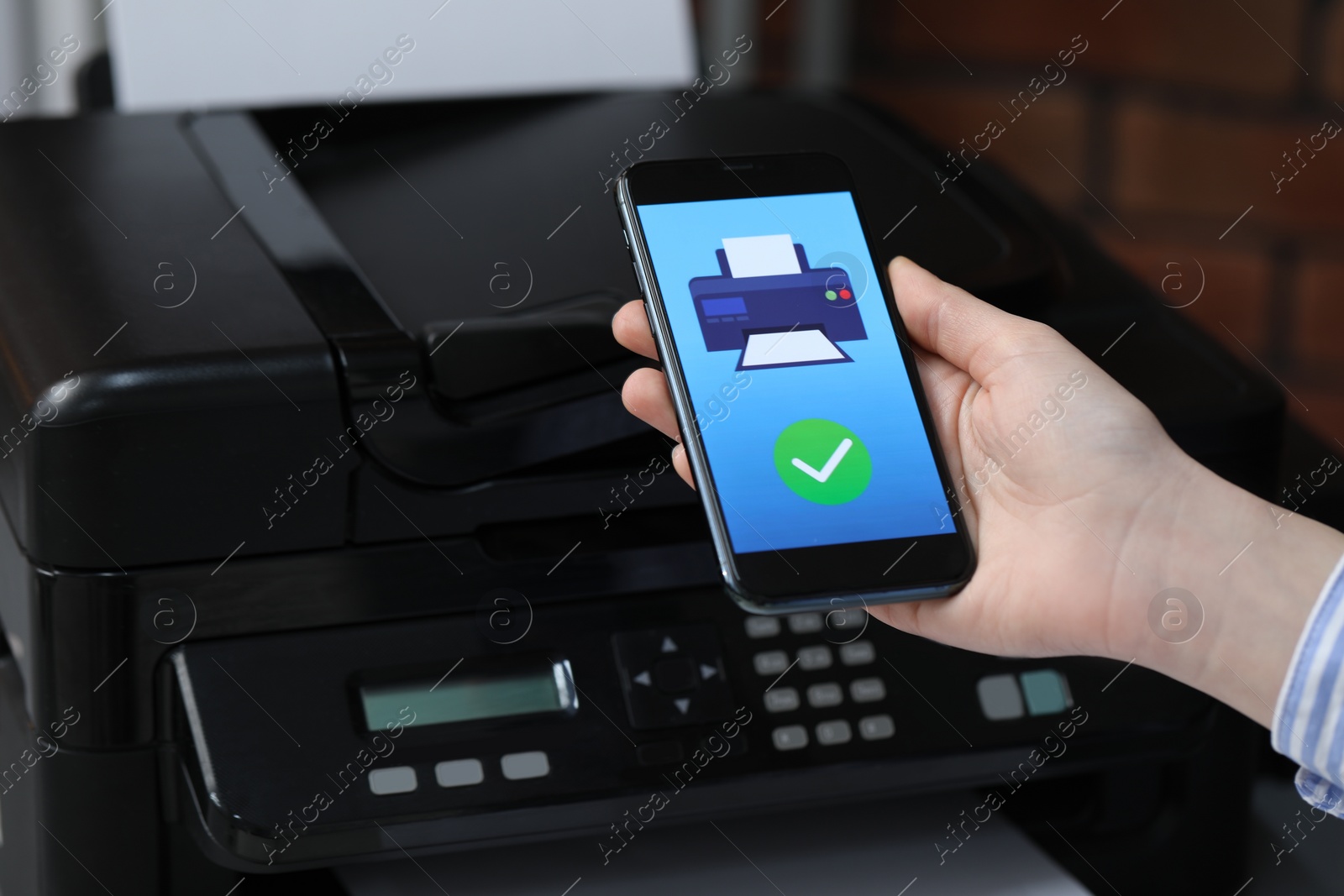 Photo of Man using printer management application on mobile phone indoors, closeup. Image on device screen.