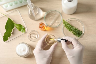 Scientist making cosmetic product at table, top view