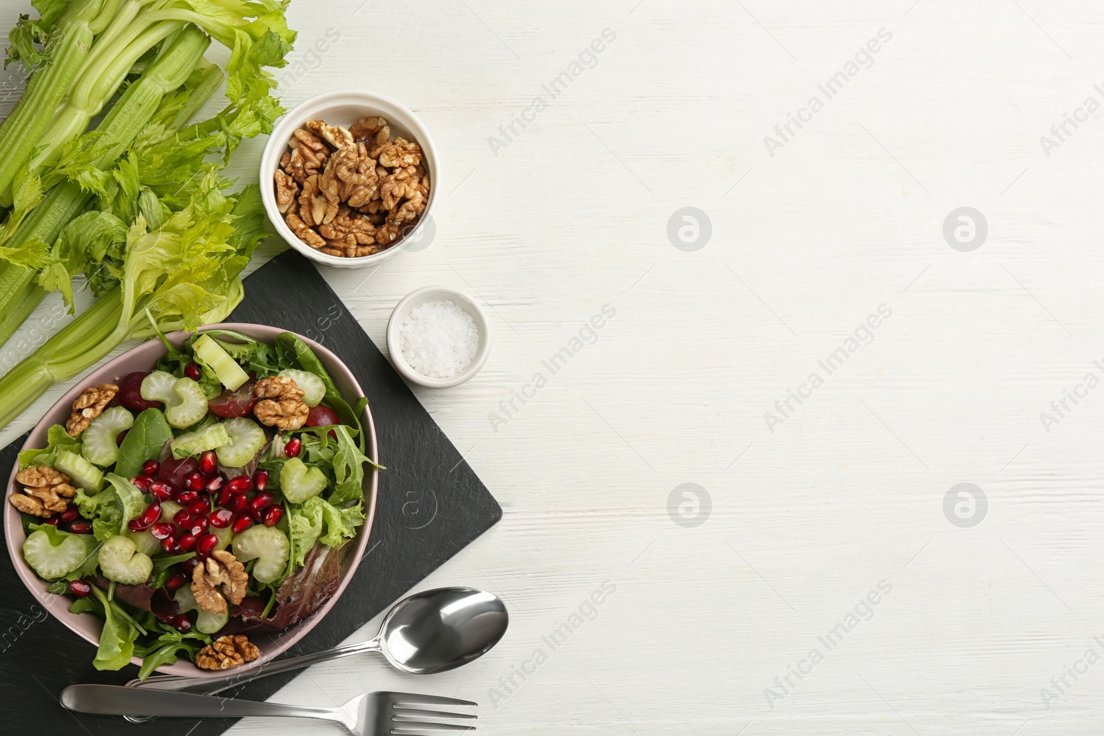 Photo of Delicious fresh celery salad served on white wooden table, flat lay. Space for text