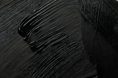 Photo of Beautiful strokes of black paint as background, closeup