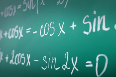 Photo of Many different math formulas written on green chalkboard, closeup