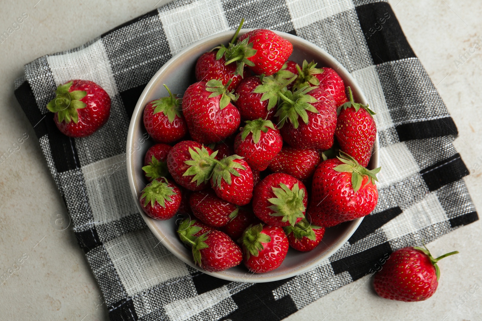 Photo of Delicious ripe strawberries in bowl on light grey table, flat lay