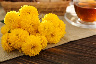 Photo of Beautiful yellow chrysanthemum flowers on wooden table, closeup. Space for text