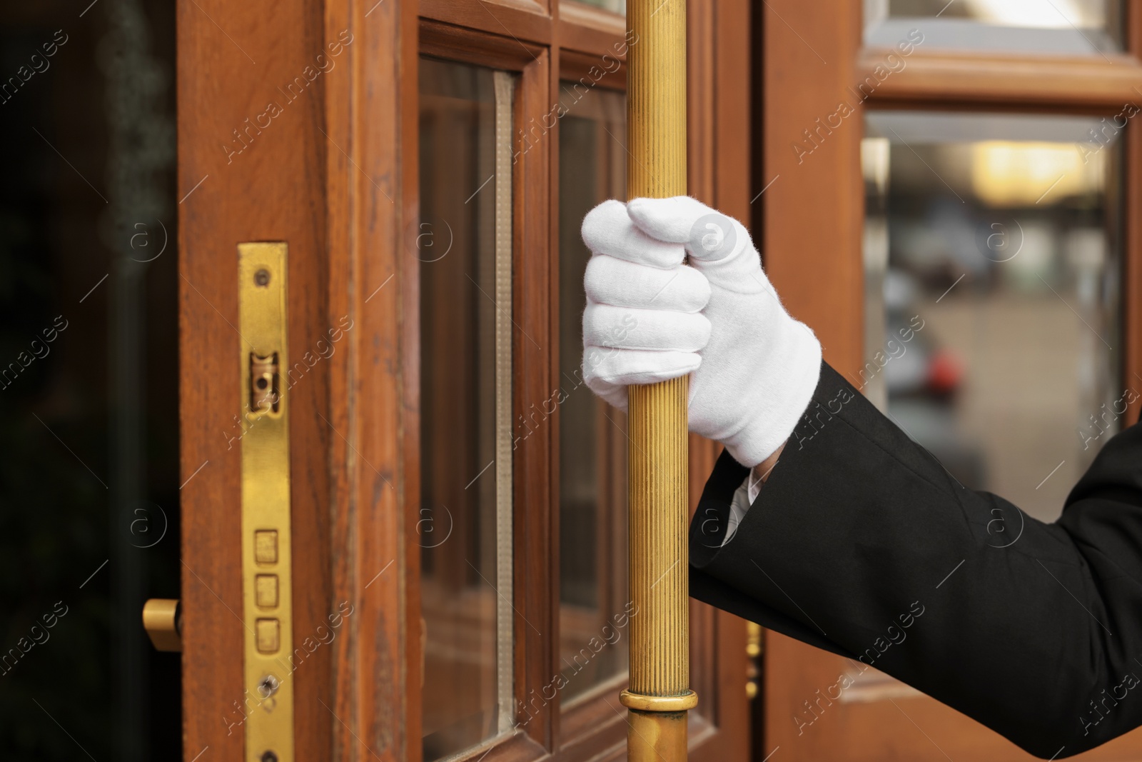 Photo of Butler in suit and white gloves opening hotel door, closeup