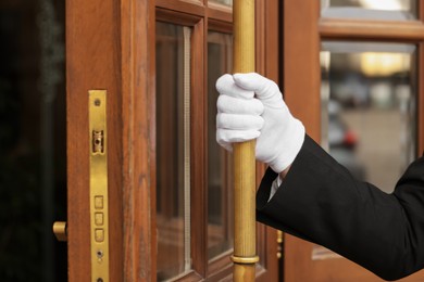 Photo of Butler in suit and white gloves opening hotel door, closeup