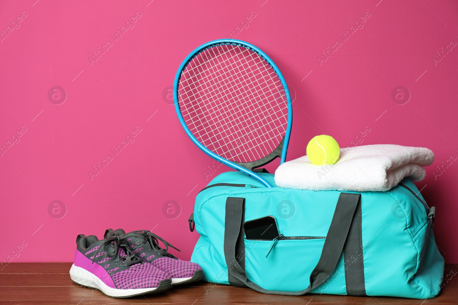 Photo of Sports bag and equipment for tennis on wooden floor against color background