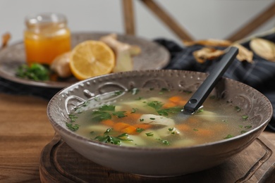 Photo of Bowl of fresh homemade soup to cure flu on wooden table