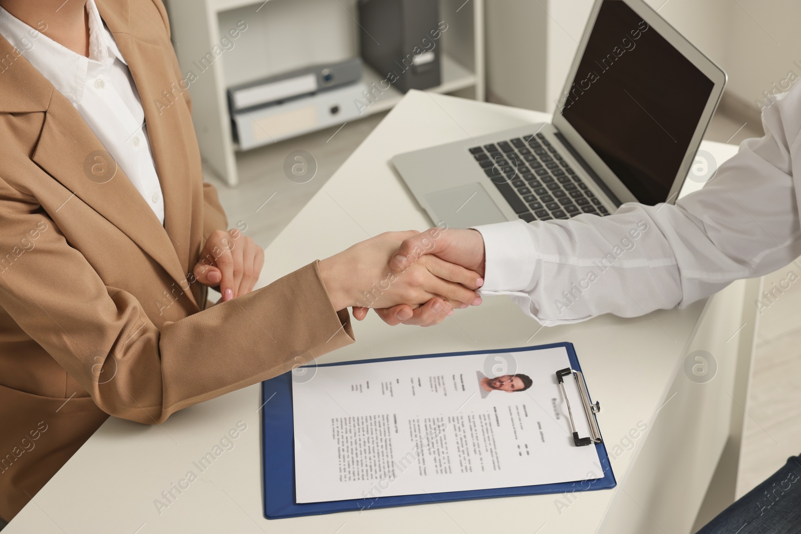 Photo of Human resources manager shaking hands with applicant during job interview in office, closeup