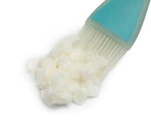 Photo of Baking dish with coconut oil and silicone brush on white background, closeup