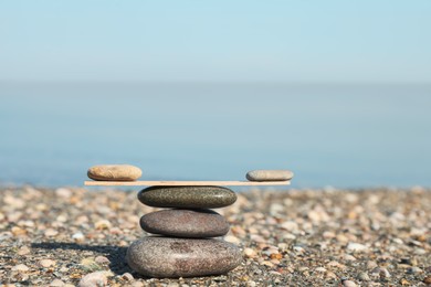 Photo of Stack of stones with wooden stick on beach, space for text. Harmony and balance concept