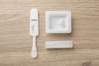 Photo of Disposable express test kit on wooden table, flat lay