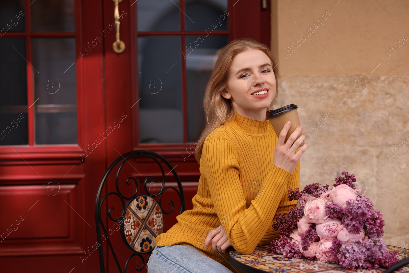 Photo of Beautiful woman with bouquet of spring flowers and coffee in outdoor cafe, space for text