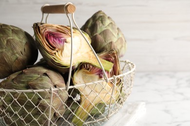 Photo of Cut and whole fresh raw artichokes on white table, closeup