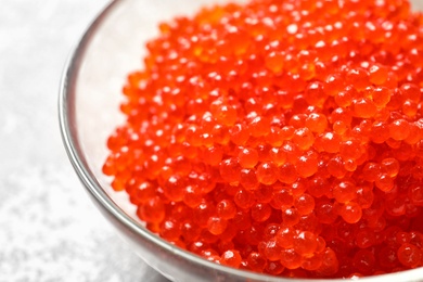 Photo of Bowl with delicious red caviar on table, closeup