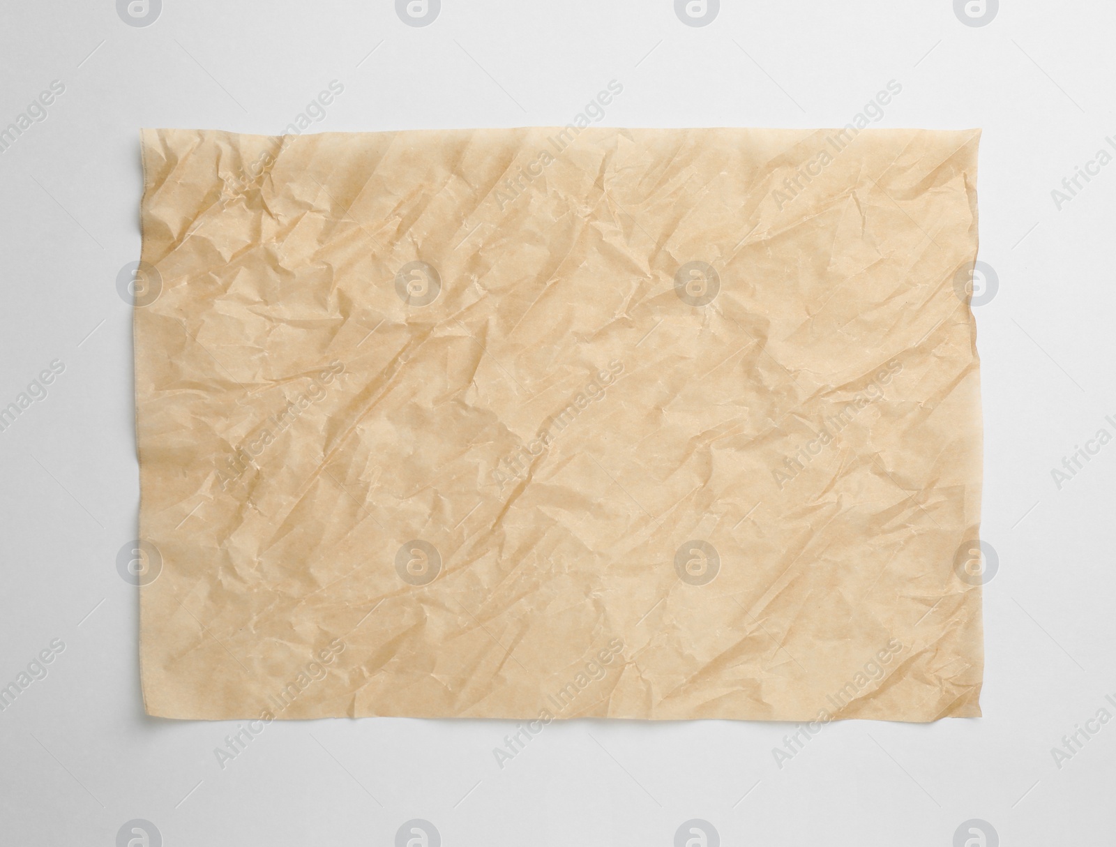 Photo of Sheet of crumpled brown baking paper on white background, top view