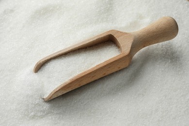 Wooden scoop on granulated sugar, closeup view