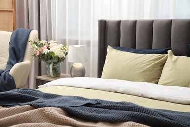 Comfortable bed with cushions and bedding in room. Stylish interior